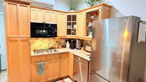 A modern kitchen with wooden cabinets, a stainless steel refrigerator, a microwave, and a sink.