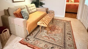 A living room with a beige sofa, patterned rug, and a framed picture on the wall.