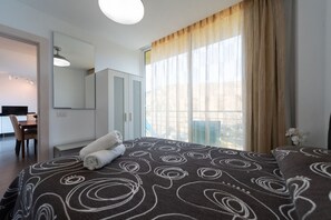 Une chambre d’hôtel avec un lit, un bureau et une grande fenêtre avec des rideaux.