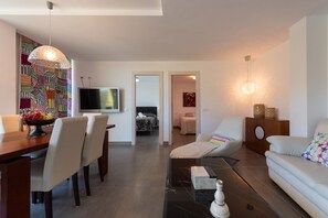 Una sala de estar moderna con comedor, un sofá, un televisor y una pared con diseño.