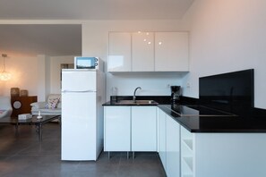 A modern kitchen with white cabinetry, a black countertop, and a built-in microwave. - Holidays & Health in Finca Oasis - Apartamento 5 by Viilas Rivero (TELDE)
