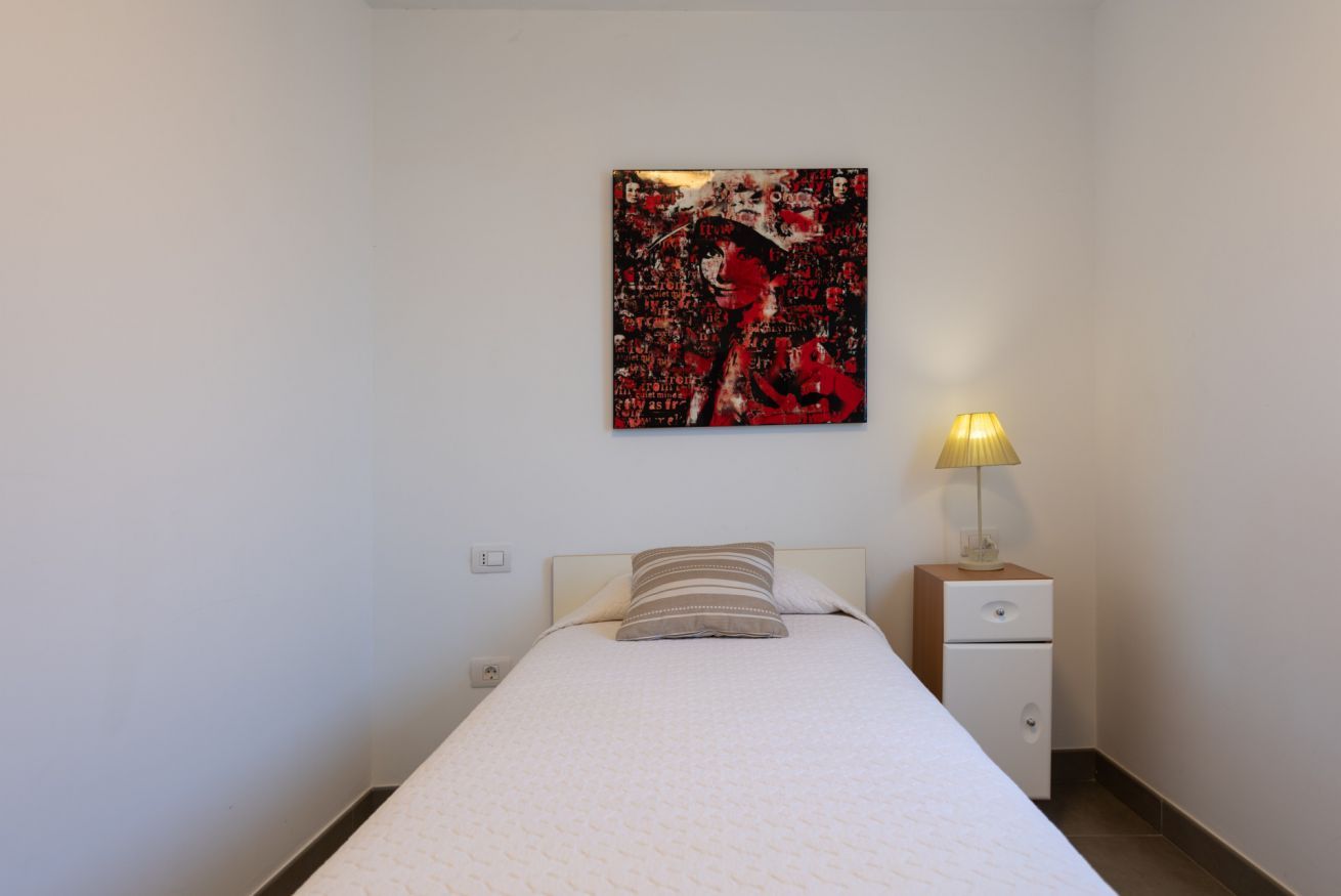 Une chambre à coucher avec un lit, une table de chevet, une lampe et un tableau accroché au mur.