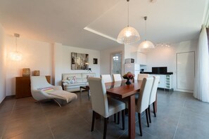 Un salon moderne avec un coin repas, un canapé et une cuisine en arrière-plan.