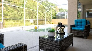 Un espacio al aire libre cubierto con techo de vidrio, muebles de mimbre, una pequeña piscina y una planta en maceta.
