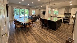 A modern kitchen with a central island, wooden flooring, and pendant lighting. - Sunapee Barn Retreat (Sunapee)