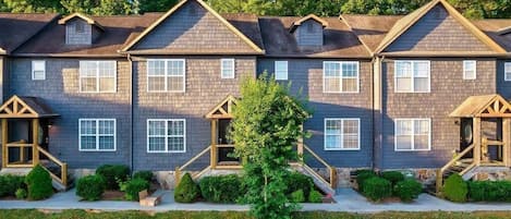 A row of two-story townhouses with a central courtyard, wooden front porches, and a well-maintained lawn.