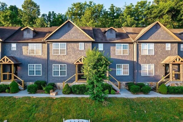 A row of two-story townhouses with a central courtyard, wooden front porches, and a well-maintained lawn.