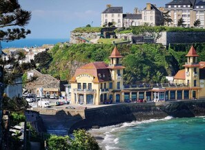 A coastal hotel with a prominent casino sign, situated on a cliff overlooking the sea.