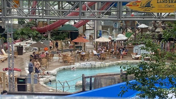An indoor water park with multiple slides, a pool area, and seating arrangements.