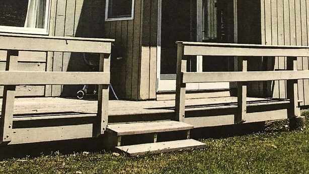 A wooden house with a porch and steps leading to the front door.