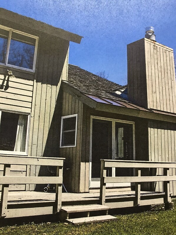A wooden house with a porch and steps leading to the front door.