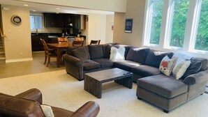 A spacious living room with a sectional sofa, a coffee table, and a dining area with a wooden table and chairs.