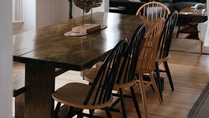 Un espace repas comprenant une table en bois, des chaises et un luminaire suspendu en fibres tressées.