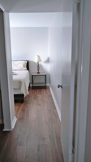 A bedroom with a bed, bedside table, lamp, and wooden flooring.