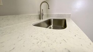 Une cuisine dotée d’un évier en acier inoxydable et d’un plan de travail en marbre blanc.