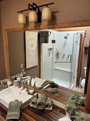 A bathroom with a large mirror, a sink, a shower, and a wooden vanity. - Beautiful Mtn Views, Hot Tub, short walk to Cafe Aroma (monthly rental) (Idyllwild-Pine Cove)
