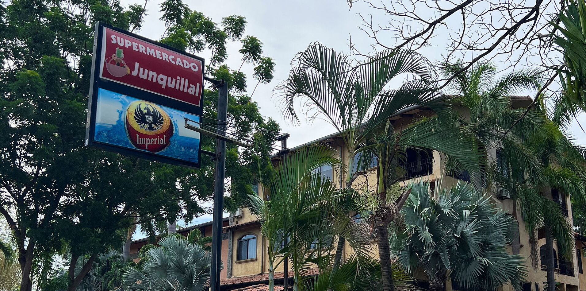 A building with a sign for 'Supermercado Junquillal' and 'Imperial' beer.