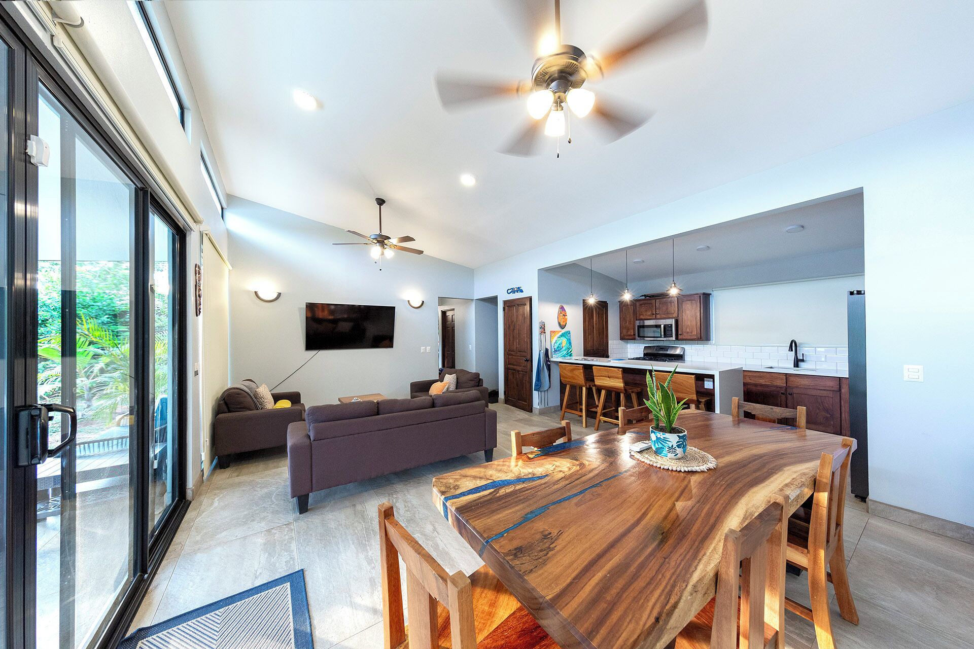 Uma sala de estar moderna com sofá, mesa de jantar e cozinha equipada, incluindo armários e televisão.