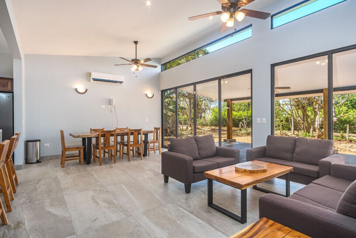 A spacious living area with a dining set, sofas, and a ceiling fan.