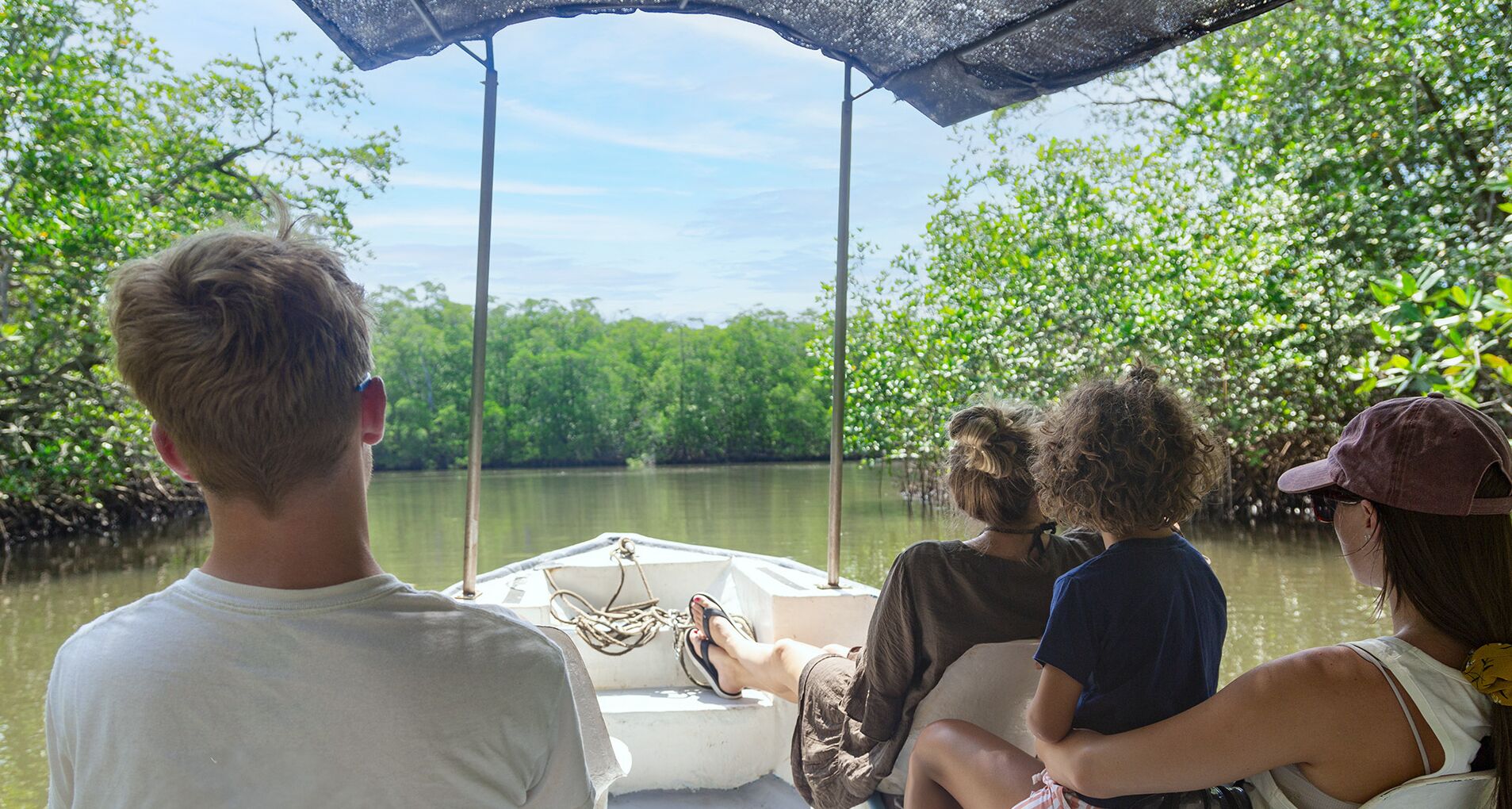 A group of people on a boat in a mangrove area.