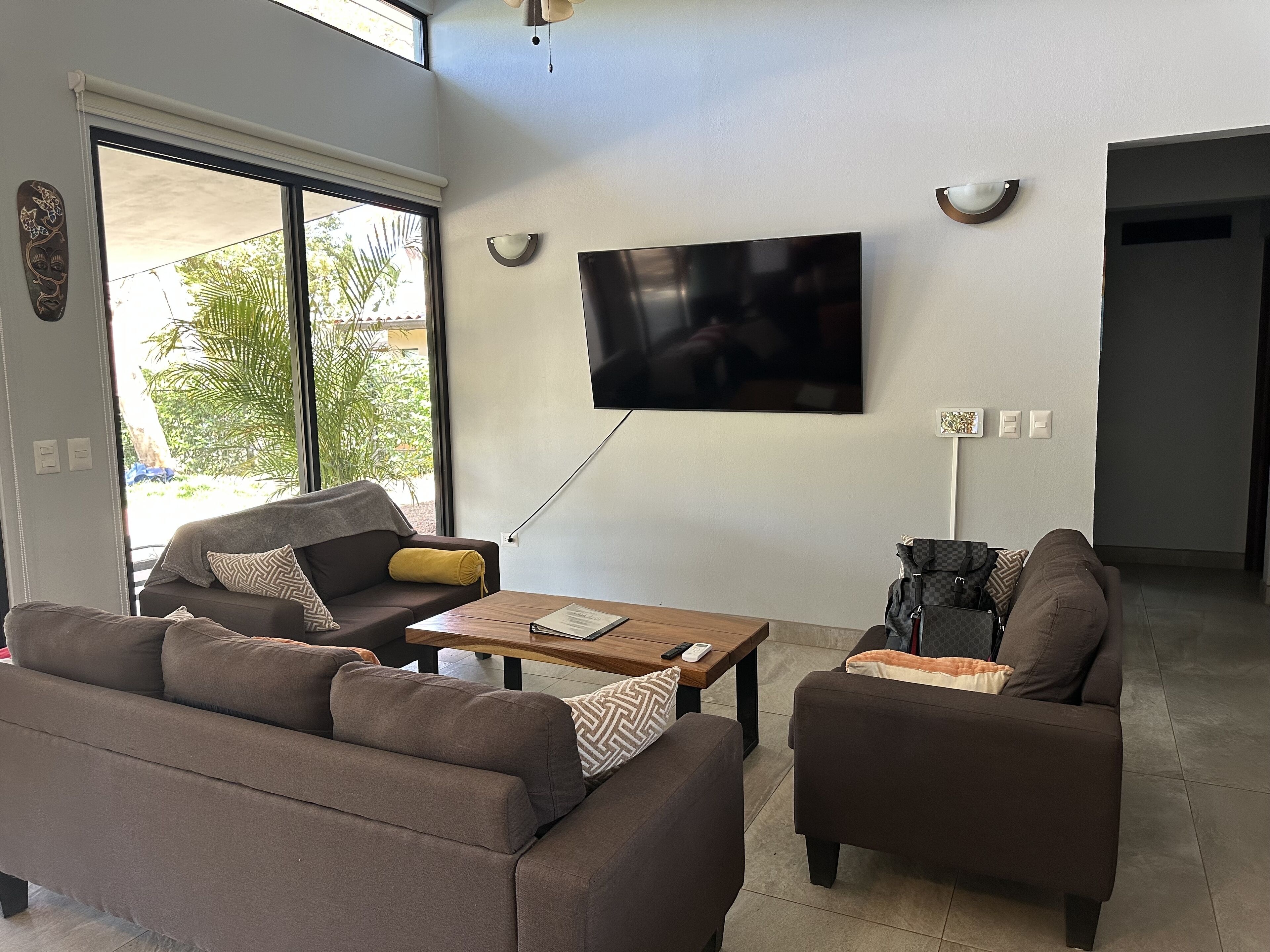 Una sala de estar moderna con un televisor de pantalla plana montado en la pared, un sofá, una mesa de centro y una mesita auxiliar.