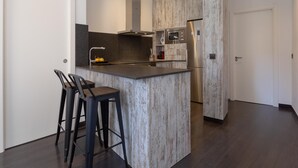 Eine moderne Küche mit Kochinsel, Edelstahlgeräten und einer Wandverkleidung aus Holzoptik.