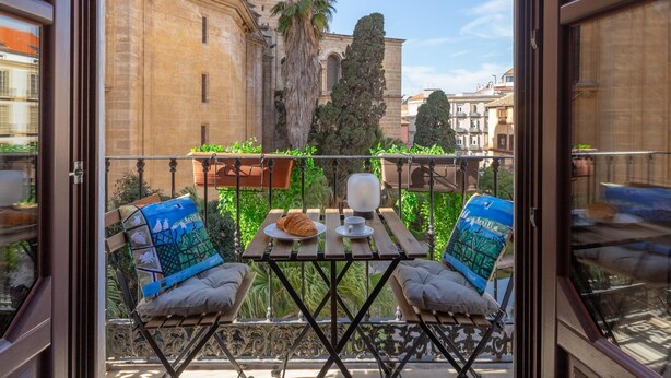 Ein Balkon mit Tisch, zwei Stühlen und Blick auf historische Gebäude.