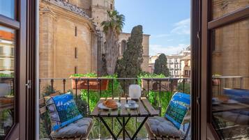 Un balcon avec une table, deux chaises et une vue sur des bâtiments historiques.
