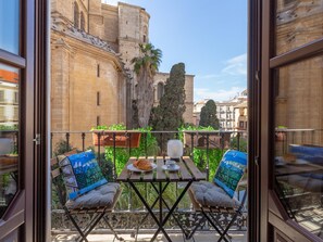A balcony with a table, two chairs, and a view of historic buildings. - Magnificent apartment with balconies and views of the Cathedral II (Málaga)