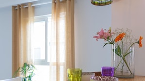 A dining table with a vase of flowers, a bowl, and a glass. - Bright apartment with terrace and parking in the center (Málaga)