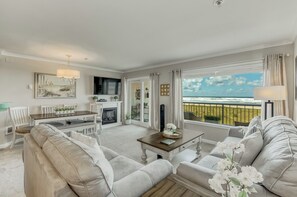Amplia sala de estar con chimenea, comedor y balcón con vista al océano.