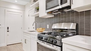 Una cocina moderna con armarios blancos, estufa de acero inoxidable y microondas.