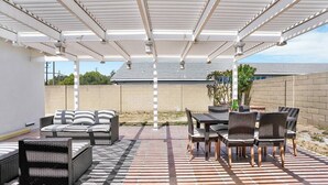 Un patio cubierto con mobiliario exterior, incluyendo sofás y una mesa con sillas.