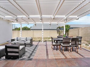 Relax in the shaded patio area with comfortable seating and a small table.