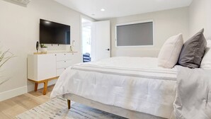 Un dormitorio con cama, televisión, cómoda y ventana.
