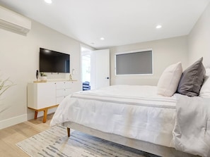 Relax in this serene bedroom with a large bed, flat-screen TV, and a dresser with mirror.
