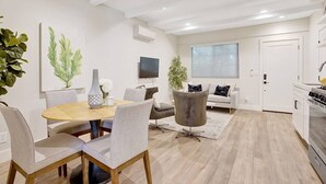 Una sala de estar moderna con comedor, cocina y un amplio ventanal.