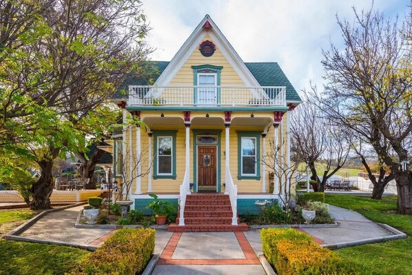 A two-story house with a front porch, a small garden, and a clear sky.