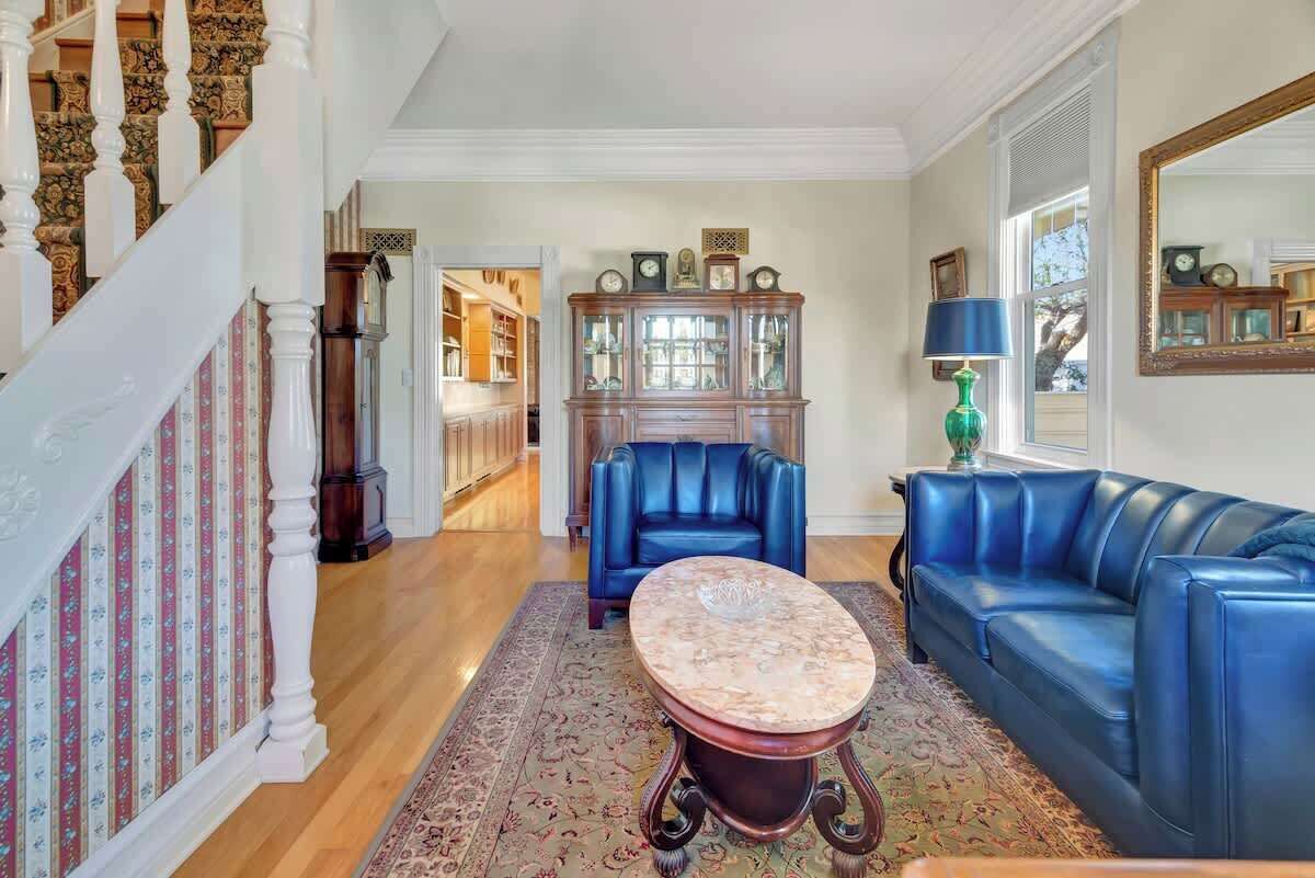 A living room with a blue leather sofa, a matching armchair, a wooden cabinet, and a patterned rug.