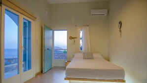 A bedroom with a bed, a door leading to a balcony, and an air conditioning unit on the wall.