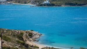 A coastal view with a white church on a hill, clear blue sea, and rocky terrain.