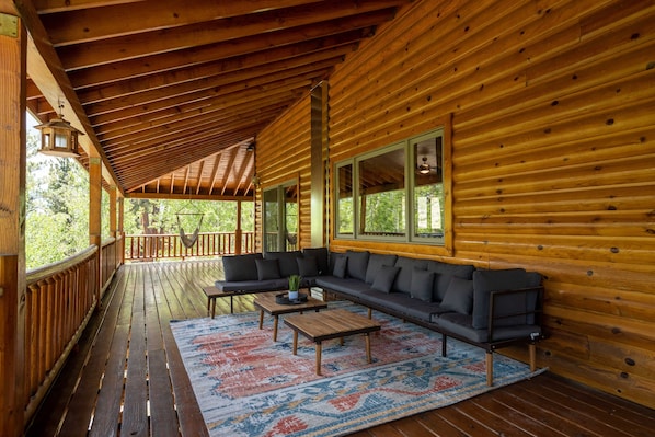 Une cabane en bois dotée d’un porche abrité, d’un grand canapé et d’une table basse.