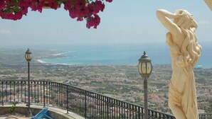 Un balcone con vista su una città costiera, una statua e un lampione.