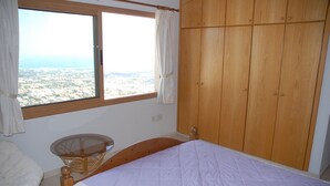 Una camera da letto con un letto, una sedia, una finestra con tende e un armadio in legno.