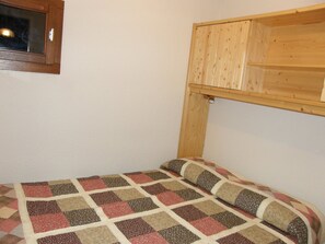 Ein kleines Zimmer mit einem Einzelbett und einem Holzbett darüber.