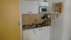 A compact kitchen with white cabinets, a microwave, a sink, and a small wooden shelf with kitchen utensils. - 2-room apartment, 4 pers, SE, balcony, collective parking (Valloire)