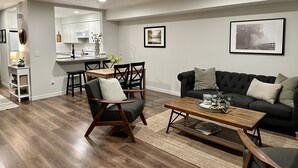 A modern living room with a dark sofa, wooden coffee table, and a dining area with a wooden table and chairs. - NEW REMODEL in the Heart of Eagle near BOISE (Eagle)