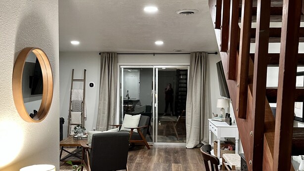 A modern living room with a wooden staircase, a dining area with a table and chairs, and a large mirror on the wall. - NEW REMODEL in the Heart of Eagle near BOISE (Eagle)