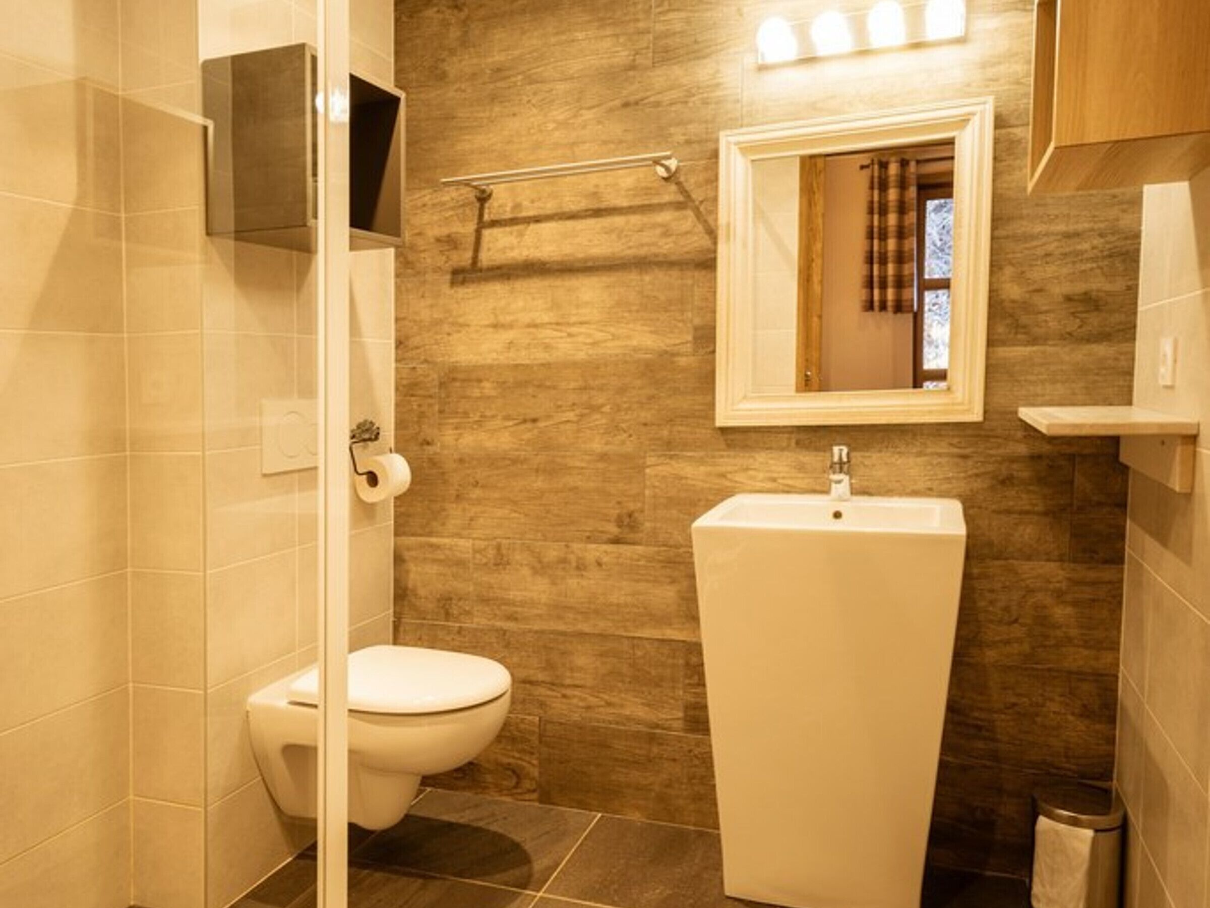 Een badkamer met een toilet, een wastafel en een spiegel.