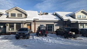 En rad moderna hus med snötäckta tak och parkerade fordon framför.